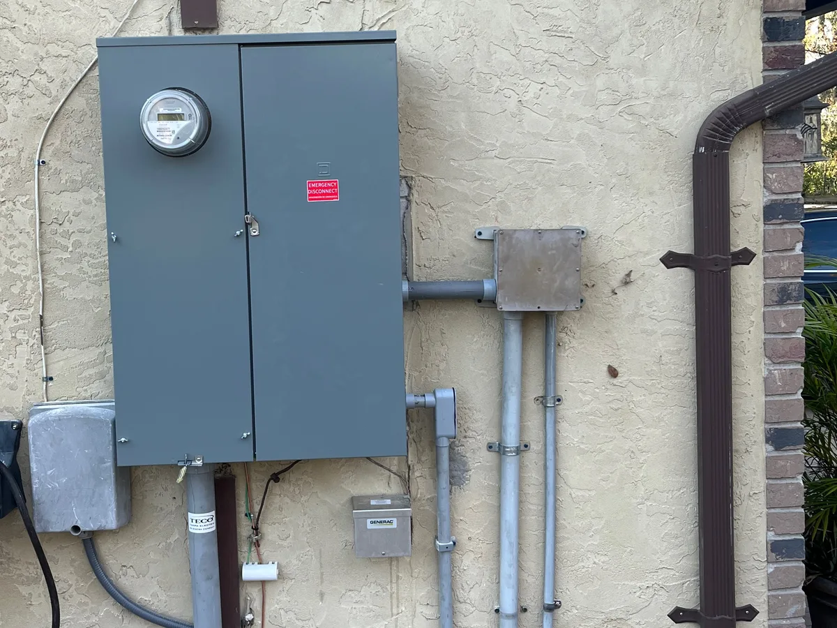 New 400-amp meter and main disconnect enclosure mounted on an exterior stucco wall, with fresh conduit runs and an emergency disconnect label — service upgrade by Far Out Design